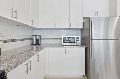 a kitchen with white cabinets and a stainless steel refrigerator at Mountain View Townhouse Fresh and Bright at Blue in Collingwood