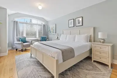 a bedroom with a large bed and a chair and a window at Mountain View Townhouse Fresh and Bright at Blue in Collingwood