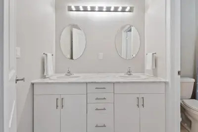 a white bathroom with two sinks and two mirrors at Mountain View Townhouse Fresh and Bright at Blue in Collingwood