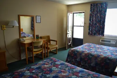 a hotel room with two beds and a table and a desk at Lighthouse Motel in Walkerton
