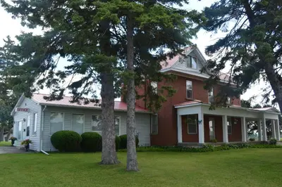 a red and white house with two trees in the yard at Lighthouse Motel in Walkerton