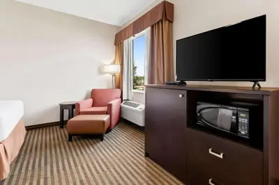 a hotel room with a flat screen tv and a chair at Best Western Plus Fergus Hotel in Fergus