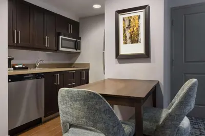 a kitchen with a wooden table and two chairs at Homewood Suites by Hilton Waterloo/St. Jacobs in Waterloo