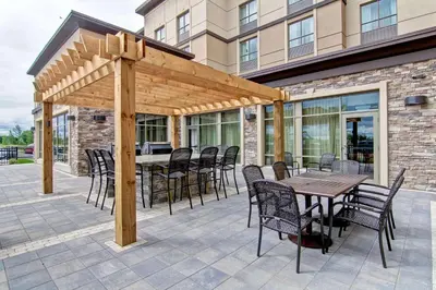 a wooden pergola on a patio with a table and chairs at Homewood Suites by Hilton Waterloo/St. Jacobs in Waterloo