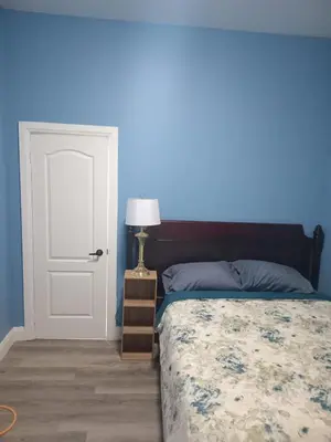 a blue bedroom with a bed and a white door at Windspire Inn in Port Elgin