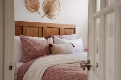 a bedroom with a bed with pillows and two mirrors at The Dainty Petunia in Picton