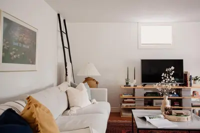 a living room with a white couch and a tv at The Dainty Petunia in Picton