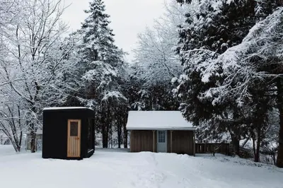 a small cabin with a door in the snow at The Dainty Petunia in Picton