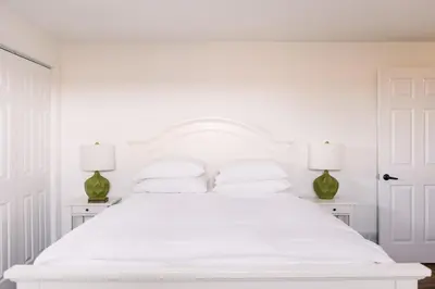 a white bedroom with a white bed with two lamps at Fox Lane - Prince Edward County Farmhouse in Picton