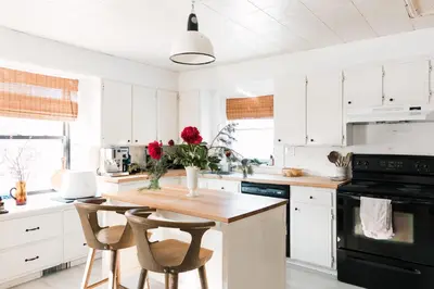 a kitchen with white cabinets and a wooden table with chairs at Hart House a fresh 3 bedroom century home in Cherry Valley
