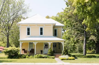 an old yellow house with a porch at Watson House - Century Home near Sandbanks in Cherry Valley