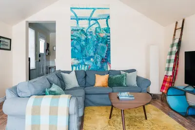a living room with a blue couch and a table at Watson House - Century Home near Sandbanks in Cherry Valley