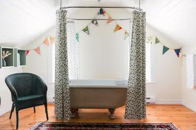 a bathroom with a tub and a chair at Watson House - Century Home near Sandbanks in Cherry Valley