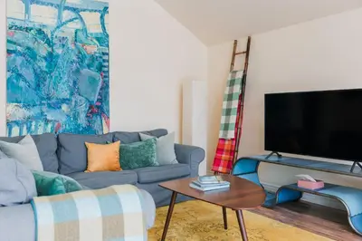 a living room with a blue couch and a tv at Watson House - Century Home near Sandbanks in Cherry Valley