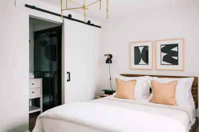 a bedroom with a bed with white sheets and pillows at Wellers Landing - Prince Edward County Lakehouse in Carrying Place