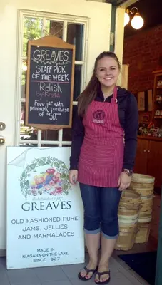 a woman is standing next to a sign at Greaves Sweet Escape in Niagara on the Lake