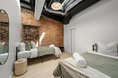 a bedroom with two beds and a brick wall at The Goodman: Front Street Flats in Belleville