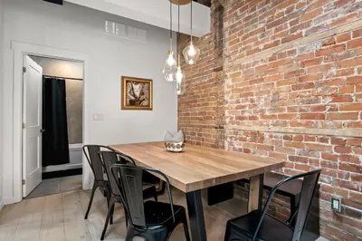 a dining room with a brick wall and a wooden table and chairs at The Goodman: Front Street Flats in Belleville