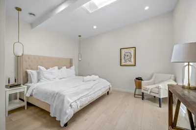 a white bedroom with a bed and a chair at The Belvedere:Front Street Flats in Belleville