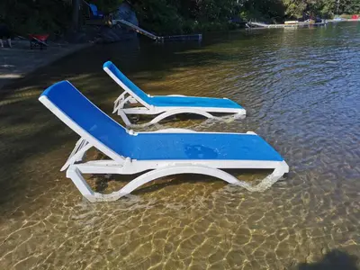 two beach chairs sitting in the water on a beach at Muskoka Shores Cottages in Port Carling