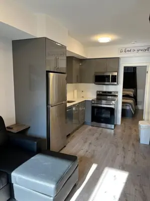 a kitchen with stainless steel appliances and a living room at Lovely one bedroom condo with free parking in Niagara Falls