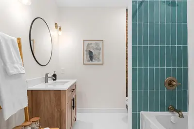 a bathroom with a sink and a shower with a mirror at The Olympia: Front Street Flats in Belleville