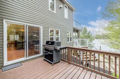 a grill on a deck next to a house at Muskoka Lakeshore Cottage Bliss in Gravenhurst