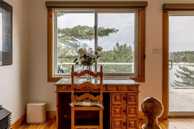 a wooden desk with a chair in front of a window at Muskoka Lakeshore Cottage Bliss in Gravenhurst