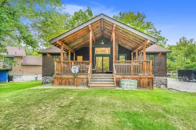 a log home with a large front porch and a house at Blue Water Dunes Cottage in Tiny