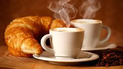 a table with two cups of coffee and a croissant at Pelican guest house. Village style living. Spend vacation time in Eco place! in Fort Erie