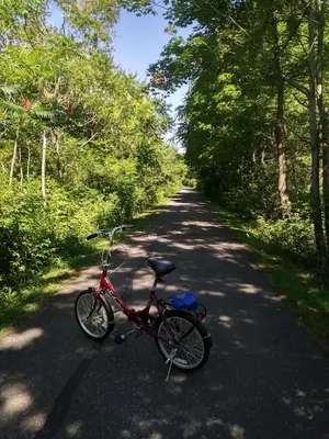 a red bike parked on a road with trees at Pelican guest house. Village style living. Spend vacation time in Eco place! in Fort Erie
