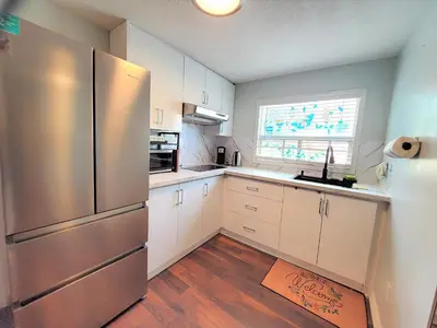 a kitchen with white cabinets and a stainless steel refrigerator at Cozy and Quiet Homestay with Private Bathroom in Toronto