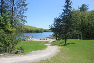 a dirt road next to a lake with a playground at Trillium Resort & Spa in Port Sydney