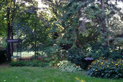 a garden with a gate and some flowers and trees at Greater Toronto B&B in Oakville