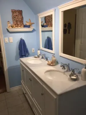 a blue bathroom with two sinks and a mirror at Greater Toronto B&B in Oakville
