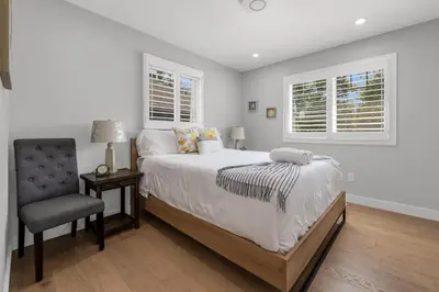 a bedroom with a bed and a chair and two windows at Lake view cottage with three ensuites and elevator in Fort Erie