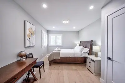 a white bedroom with a bed and a desk and a table at Lake view cottage with three ensuites and elevator in Fort Erie
