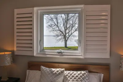 a window above a bed with a tree seen through it at Lake view cottage with three ensuites and elevator in Fort Erie