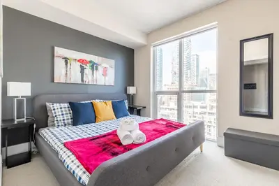 a bedroom with a bed and a large window at Luxury King Bed Condo with Stunning City Views in Toronto