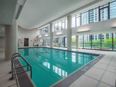 a large swimming pool with blue water in a building at Lakeview Condo in Downtown with Free Parking. in Toronto