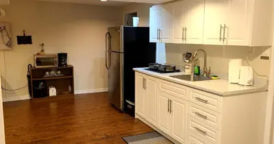 a kitchen with white cabinets and a black refrigerator at Spacious and bright unit with natural light. in Pickering