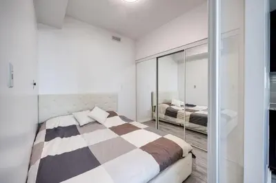 a bedroom with a bed and a mirror at Cityscape 1BR Condo with Private Balcony amd WFH setup in Toronto