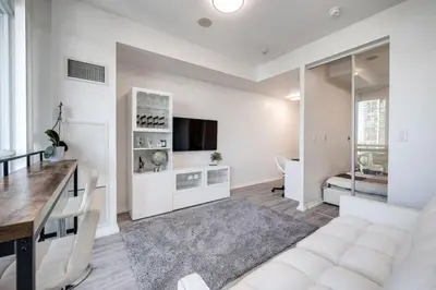 a living room with a white couch and a table at Cityscape 1BR Condo with Private Balcony amd WFH setup in Toronto