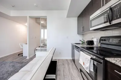 a kitchen with a couch in the middle of it at Cityscape 1BR Condo with Private Balcony amd WFH setup in Toronto