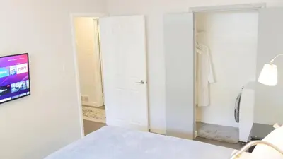 a white bedroom with a bed and a tv at Richview Gardens Suite, 3-bdr in Toronto