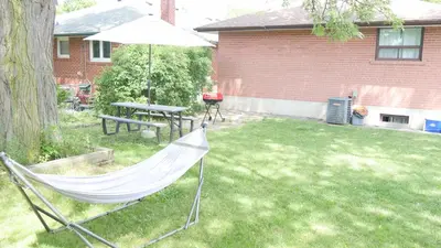 a hammock in a yard with a picnic table and a table at Richview Gardens Suite, 3-bdr in Toronto