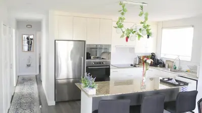 a kitchen with white cabinets and a stainless steel refrigerator at Richview Gardens Suite, 3-bdr in Toronto