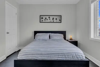 a bedroom with a bed with a striped blanket at Oshawa Family Haven - Luxury 7BR Villa with Cozy Fireplaces & Hot Tub in Oshawa