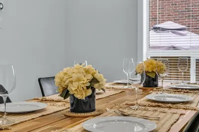 a dining room table with plates and flowers in vases at Oshawa Family Haven - Luxury 7BR Villa with Cozy Fireplaces & Hot Tub in Oshawa