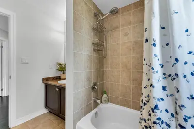 a bathroom with a tub and a shower with a shower curtain at Oshawa Family Haven - Luxury 7BR Villa with Cozy Fireplaces & Hot Tub in Oshawa